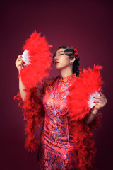 Beautiful chinese woman wearing traditional red dress holding fans up posing on isolated background in vertical