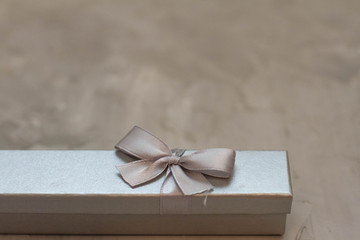 grey gift box with a bow on a concrete background. Gift for birthday, Valentine's Day, Christmas, New year, mother's Day, women's day, February 23. space for text. banner. postcard.