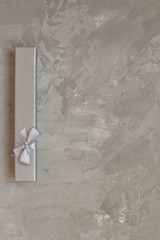 grey gift box with a bow on a concrete background. Gift for birthday, Valentine's Day, Christmas, New year, mother's Day, women's day, February 23. space for text. banner. postcard.