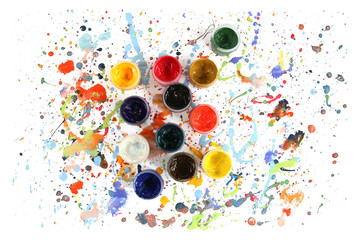Jars with gouache paints on colorful paint splashes background. Plastic cans with multi-colored dye...