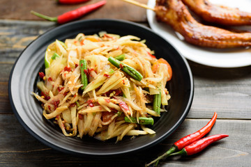 Thai food (Som Tum), spicy green papaya salad eating with grilled chicken wing