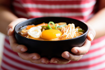 Kimchi soup with mushroom and egg yolk in a bowl holding by hand, Korean food