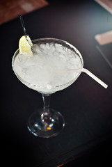 White cocktail on bar counter. Drink with martini, gin, tequila and lime. Glass with booze on a...