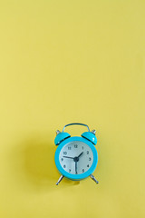 Creative flat lay vintage blue clock on yellow background. Top view background concept in minimal style