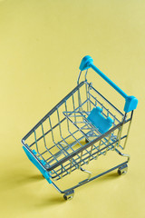 close-up photo of shopping trolley on yellow background.Top view of minimalistic photo of pushcart