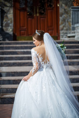 bride in a beautiful white and long dress on a background of a brick building