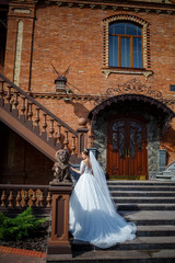 Fototapeta na wymiar bride in a beautiful white and long dress on a background of a brick building