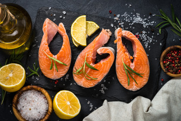 Raw salmon steak on black top view.