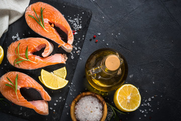 Raw salmon steak on black top view.