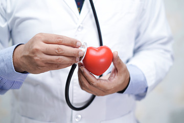 Doctor with stethoscope holding red heart in his hand in nursing hospital ward : healthy strong medical concept