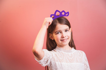 a beautiful girl in a white dress playfully poses on a pink background