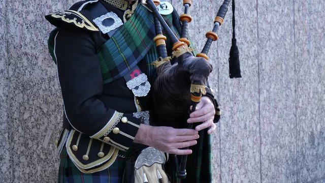Bagpiper in Scotland wearing traditional tartan kilts playing the pipes. Scottish culture. 