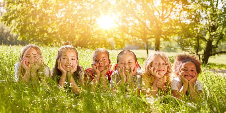 Multicultural group of children lies on meadow in summer