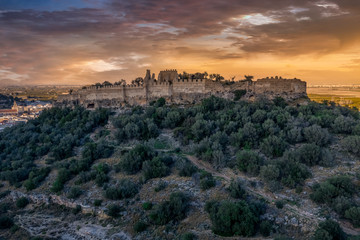 Aerial view of Corbera medieval Gothic castle in ruins on a hilltop near the coast with walls and a standalone tower in Spain 