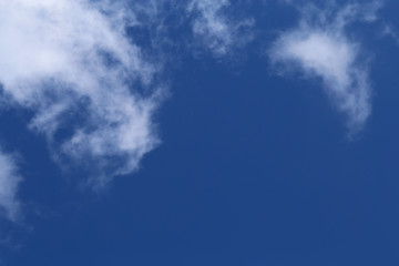 Blue sky with cute white clouds. Sunny summer day sky. Beautiful, relaxing background image that symbolizes happiness, religion and freedom. Color image.