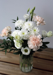 Super cute, light color flower bouquets including baby pink and white dianthus flowers with white chrysanthemum flowers, and some other white flowers. Photographed with a white wall on the background.