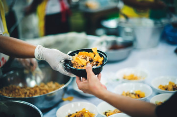 Food donation to hungry people, poor hands waiting to receive free food from volunteers