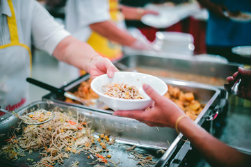 Food donation to hungry people, poor hands waiting to receive free food from volunteers