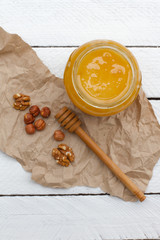 honey with nuts. Jam in a glass jar with a wooden spoon. yellow sweet honey. beekeeper. natural sweets. hazelnuts and walnuts. health food. space for text. vitamins.