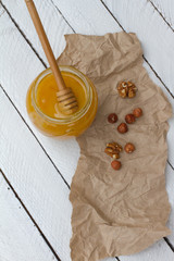 honey with nuts. Jam in a glass jar with a wooden spoon. yellow sweet honey. beekeeper. natural sweets. hazelnuts and walnuts. health food. space for text. vitamins.