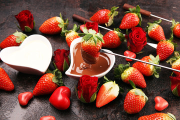 Valentine Chocolate fondue melted with fresh strawberries and dark and white chocolate. Red roses and sugar hearts for Valentines Day. Valentine Background
