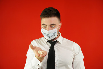 A man in a white shirt in a mask with the inscription coronavirus with pills in his hand. Coronavirus concept. Coronavirus epidemic. The cure for the virus.