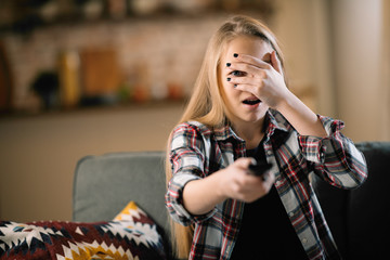 Teenage girl watching TV. Pretty girl watching horror film.