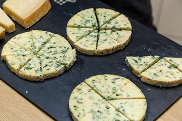 A cheese cutting from different types of cheese on a wooden board