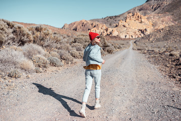 Lifestyle portrait of a carefree woman dressed casually in jeans and red hat enjoying travel on the desert valley