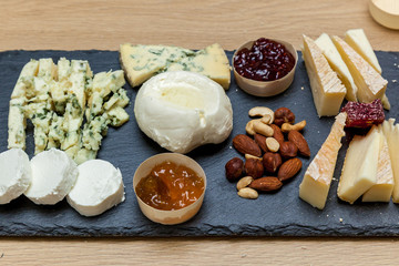 A cheese cutting from different types of cheese on a wooden board