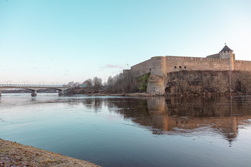 Obraz premium Beautiful river embankment overlooking the medieval castle and the fortress wall. Walk in the early morning in winter