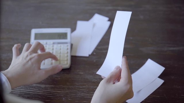 電卓でレシートの数字を計算する女性の手元
