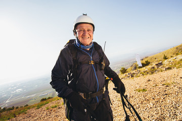 Active senior paraglider on the ground prepairs to fly.