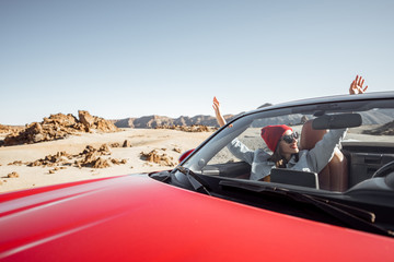 Young woman traveling by convertible car on the picturesquare desert valley, sitting at the...