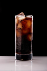 cola with ice on a black background
