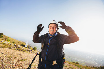 Active senior paraglider on the ground prepairs to fly.