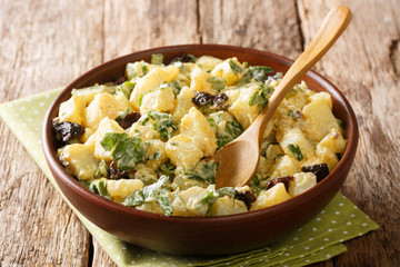 Mediterranean potato salad with herbs, spices and dried olives with yogurt dressing closeup in a...