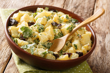 Traditional Moroccan potato salad with herbs, spices and dried olives seasoned with yogurt close-up in a bowl. horizontal