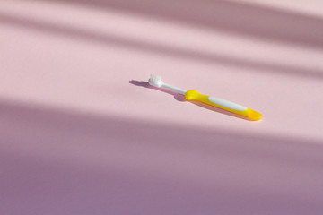 Fototapeta premium yellow toothbrush on a pink background. concept of dentistry and healthy teeth. children's toothbrush. the view from the top. space for text.