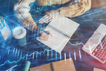 Forex graph on hand taking notes background. Concept of research. Double exposure