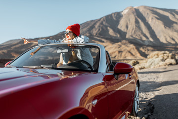 Lifestyle portrait of a young woman enjoying road trip on the desert valley, getting out the...