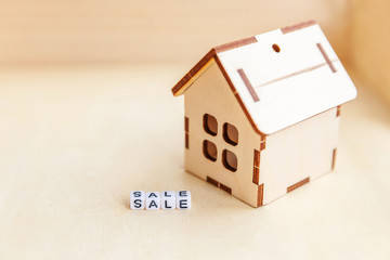 Miniature toy model house with inscription SALE letters word on wooden backdrop. Eco Village, abstract environmental background. Real estate mortgage property insurance sweet home ecology rent concept