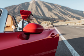 Woman in red hat traveling by cabriolet on the desert valley, getting out the car on the roadside...