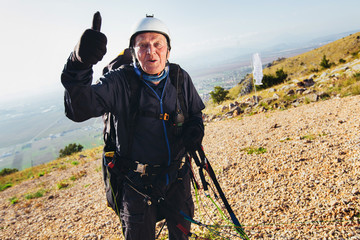 Active senior paraglider on the ground prepairs to fly.