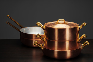 Shiny vintage copper cookware over dark background