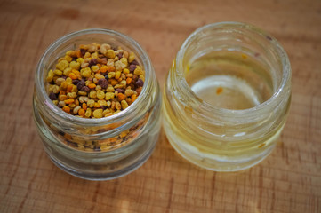 pollen and may honey in small glass jars standing on a wooden board