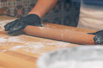 Chef hands in black gloves prepares dough close up