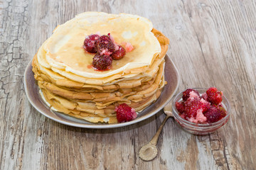 Stack of fresh homemade pancakes with red fresh strawberries in sugar in a plate on an old wooden table, vintage background, rustic style, copy space