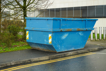 Blue color metal skip or dumpster in a street, selective focus. Concept renovation and construction job.