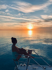 Silhouette of woman sitting on a boat at sunset